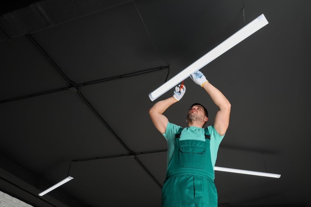 Electrician installing ceiling light fixture